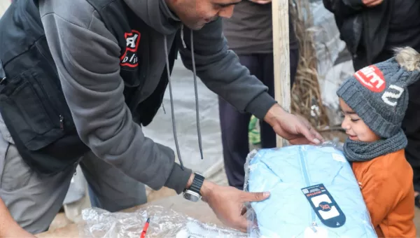 child being handed package by War Child member of staff