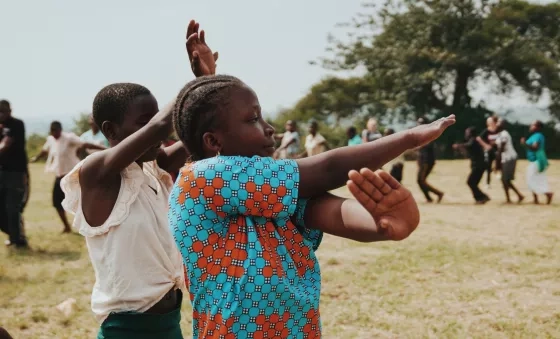 Participants laugh as they dance together outside their War Child supported school in Uganda.