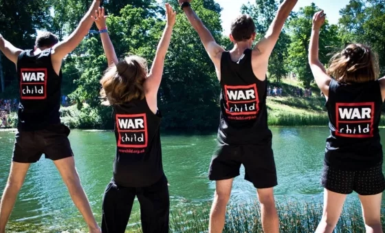 War Child staff jump in the air whilst volunteering at Wilderness Festival.