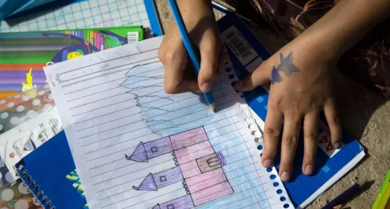 Participant Soleen drawing a pink castle on some lined paper.