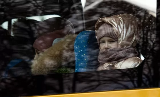 Little girl looking out of the window of the bus taking her to the safe zone.