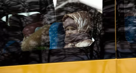 Little girl looking out of the window of the bus taking her to the safe zone.