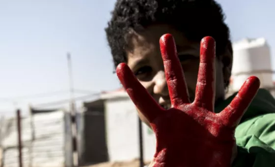 A boy with his hand painted red for Red Hand Day. 