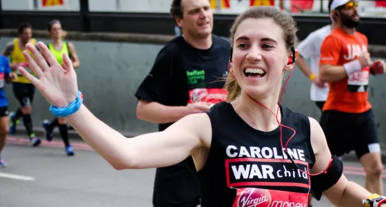 A Team War Child runner waves as they complete their half marathon