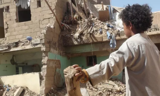 A child looking at a destroyed home in Yemen. 