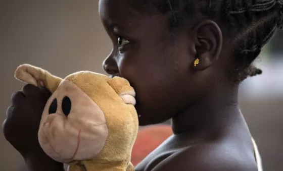 Little girl in the Central African Republic hugs a teddy bear in early childhood development centre.