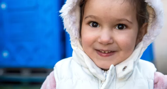 Girl in Ukraine smiling with white coat on and hood up