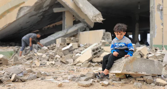 Child sitting on rubble in Gaza.