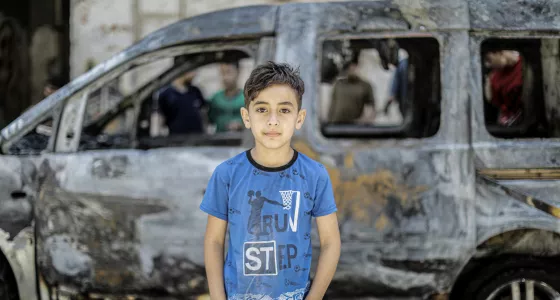 Boy in Gaza near destroyed car