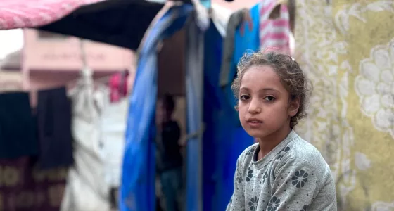 A girl sat outside in a refugee camp in Gaza. 