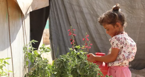 Sama watering flowers in a refugee camp in Syria.