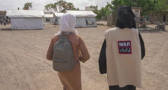 A War Child staff memebr and child walking together.