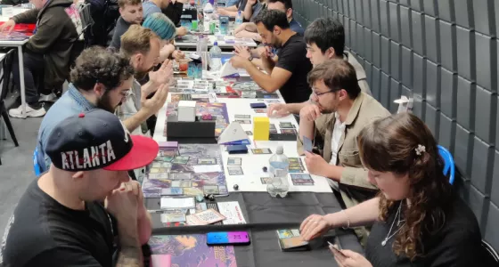 People sitting at a table playing Magic the Gathering.