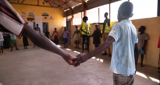 A group of children standing in a circle and holding hands. 