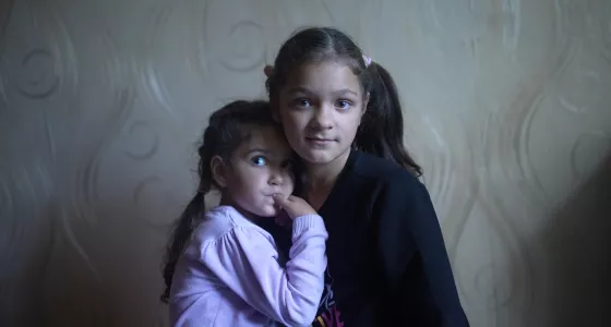 two sisters looking at the camera, one leaning into the other