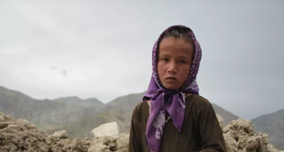 girl looking into camera in front of rubble