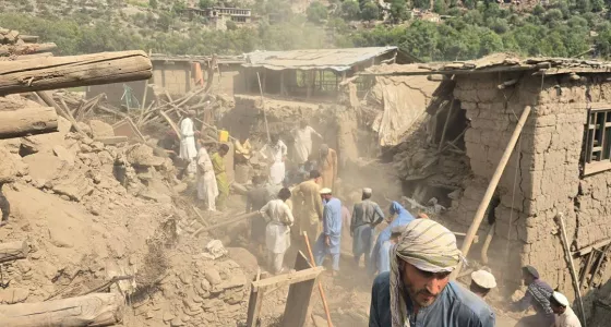 Afghan men surrounded by destroyed houses and rubble.