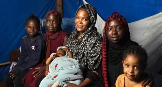 Women and their children sitting together in a tent.