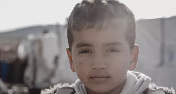 small boy in coat looks at camera