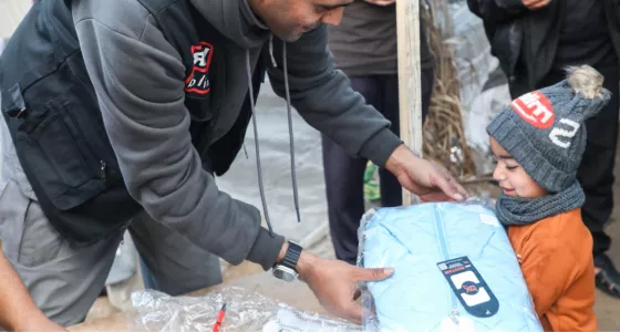 child being handed package by War Child member of staff