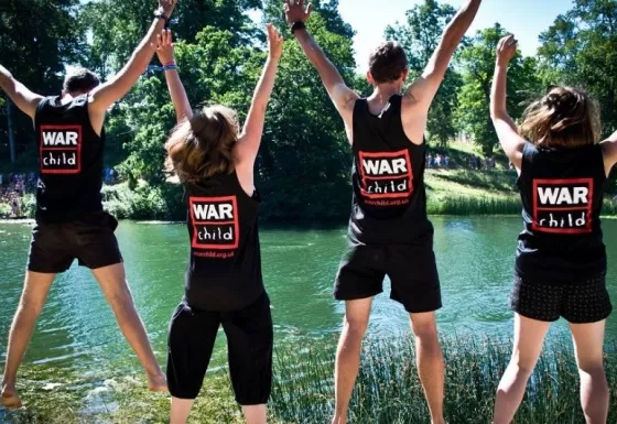 War Child staff jump in the air whilst volunteering at Wilderness Festival.