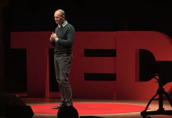Rob Williams, CEO of War Child UK, stands on stage speaking to a crowd at his TEDX Talk on Children in War at Warwick University in 2013.