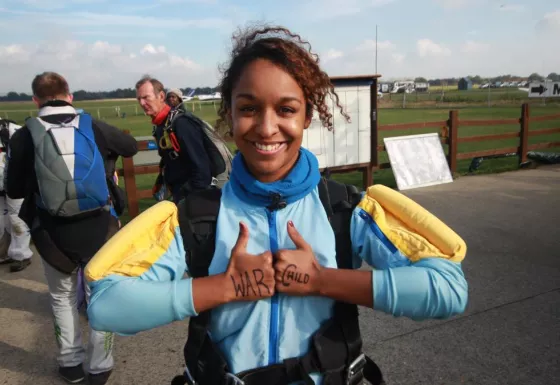 A Team War Child skydiver giving the thumbs up after completing their jump