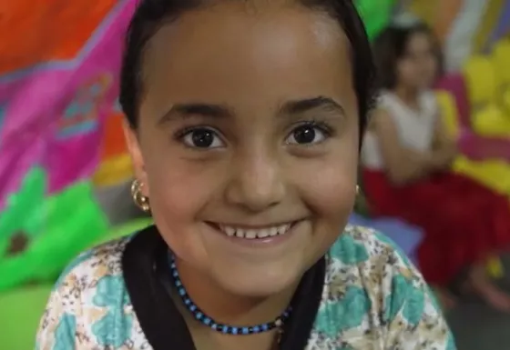 Little girl at War Child centre smiles into the camera.