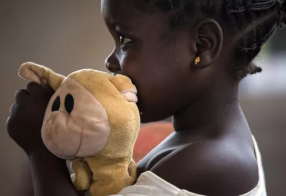 A child in War Child's child-friendly spaces cuddles her toy