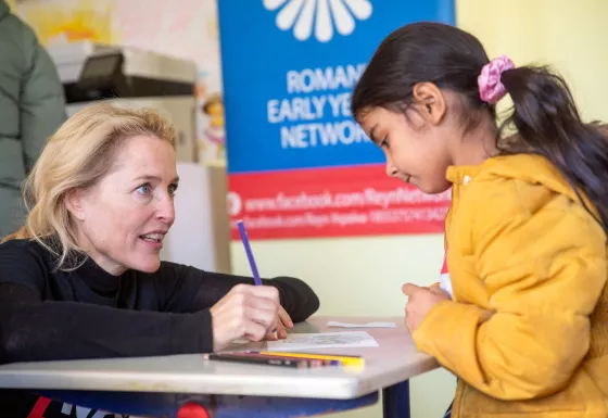 Gillian Anderson with a young child helping a child in a school in Ukraine