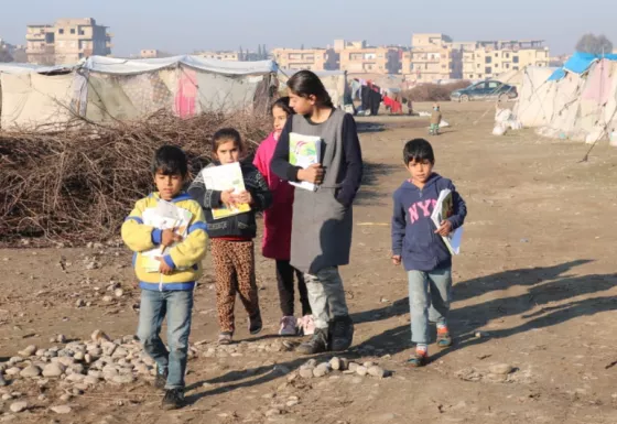 Children walking through a refugee camp, Syria. 