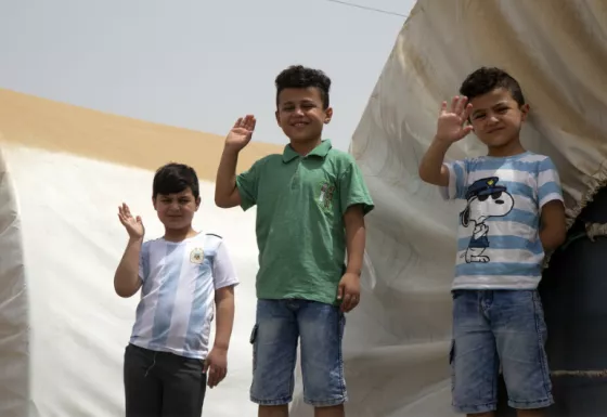 Children waving at a camp in Iraq.