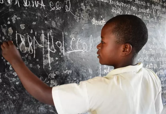 Lamegi drawing on a chalk board in DRC.