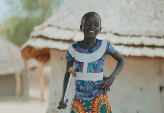 Adit standing near her home and smiling.