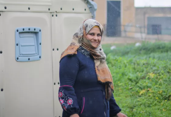 Raina standing in front of a temporary home in Syria. 