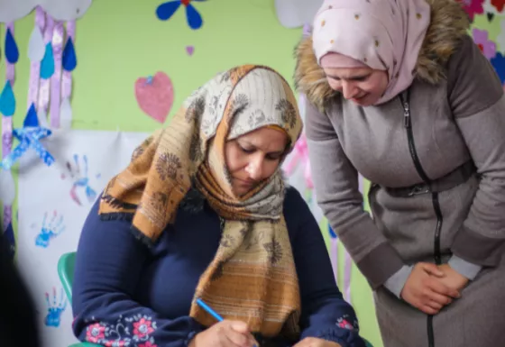 Rania recieving assistance from a War Child staff member.