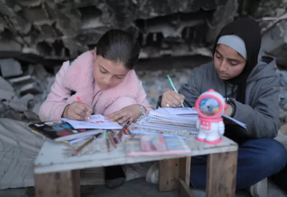 Two girls sat with books and pencils