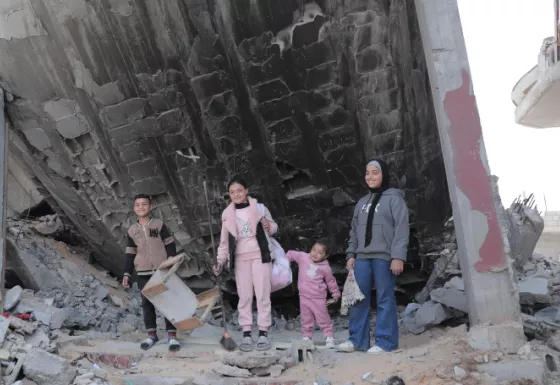 4 children standing underneath rubble.