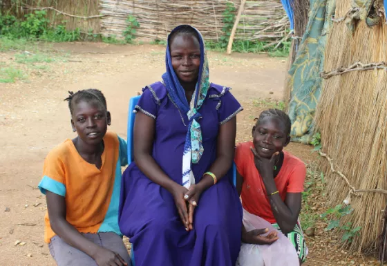 Two children sitting with their adult caregiver