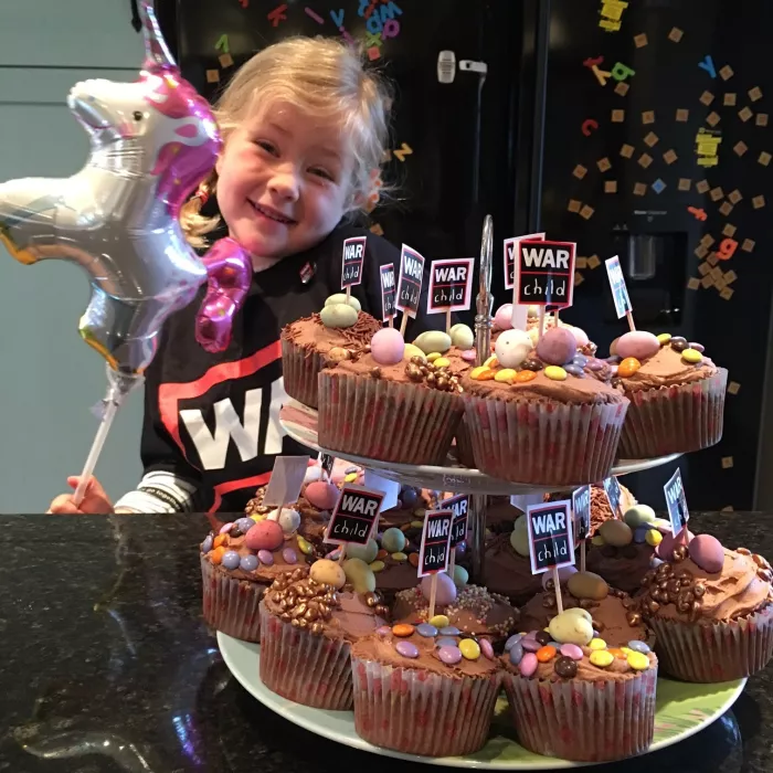 5 year old Isabella celebrating her birthday in aid of War Child, wearing a War Child t-shirt with War Child cupcakes