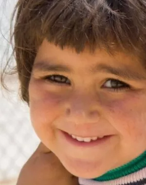 Participant smiles to the camera in a camp for those displaced by conflict.