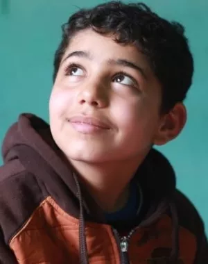 Boy smiling as he completes his school work.