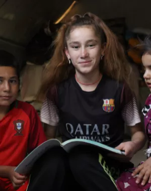 Participant Nadia reads to her siblings at their home in a displacement camp in Iraq.