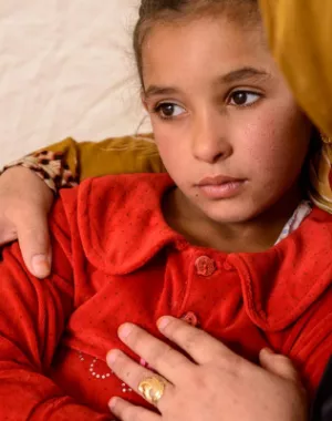 Iraqi girl sits in her mother arms.