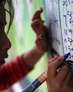 Child writing on a board in a temporary learning space.